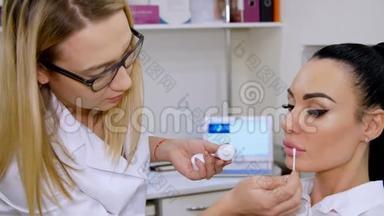<strong>医务</strong>处，医生在注射透明质酸后，用棉签在病人的嘴唇上涂上一层化妆霜